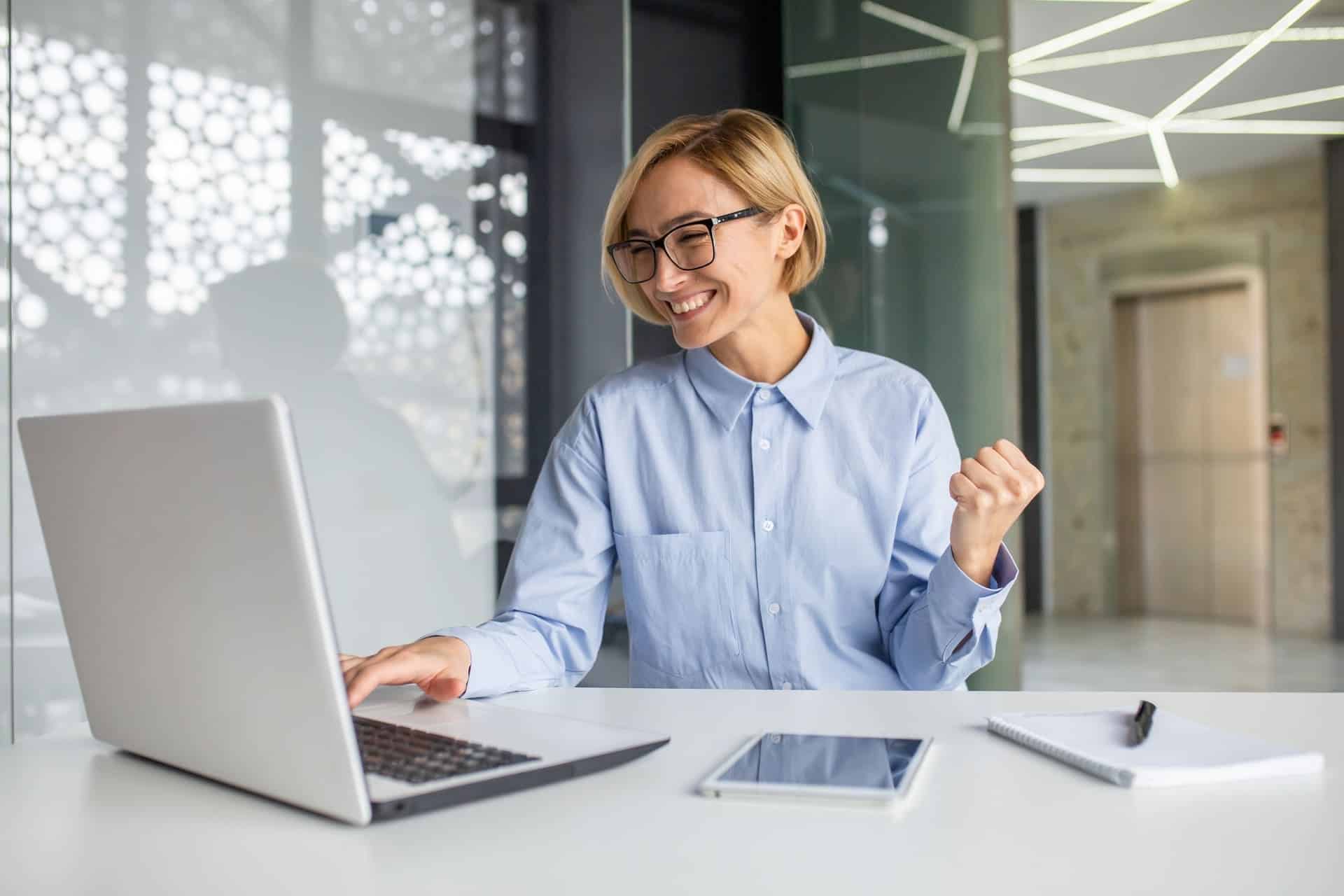 frau feiert erfolg vor laptop